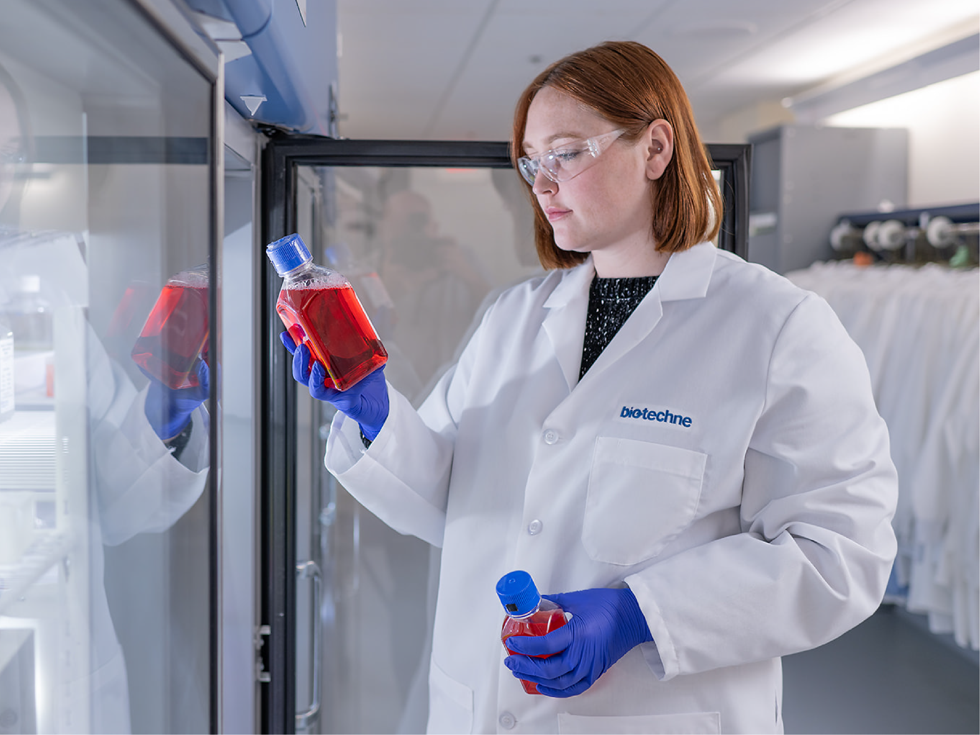 Scientist holding cell culture media bottles