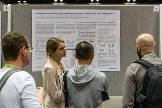 A scientific poster being presented at a conference to three onlookers.