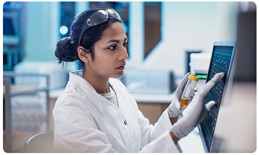 scientist with vial at computer